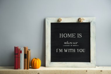 chalkboard frame on the grey wall with books and pumpkin HOME IS clipart