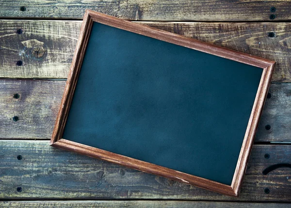Chalkboard sign over old wooden table background — Stock Photo, Image