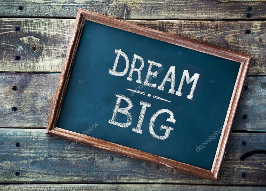 Hand drawn chalkboard sign DREAM BIG over old wooden table backg Stock Photo by ©jusakas 58117015