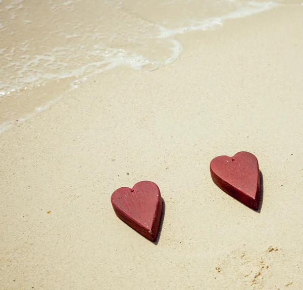 Dos corazones rojos de madera en la arena —  Fotos de Stock