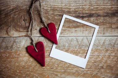 Sevgililer polaroid çerçeve rustik ahşap zemin üzerine iki kırmızı kalp şeklinde