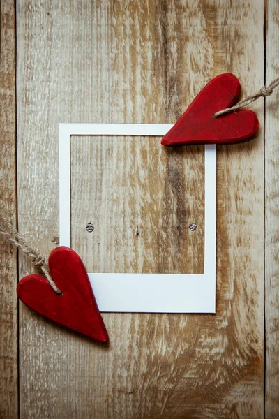 Dos valentines rojos en forma de corazón en el fondo rústico de madera con marco polaroid — Foto de Stock