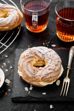 Ev yapımı choux pastası Paris Brest badem gevreği ve şeker tozu ile.