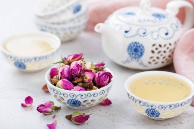 Açık gri arka planda güllü bitkisel çay.