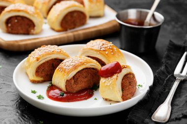 Lezzetli ev yapımı sosisli rulo domates sosuyla servis ediliyor..