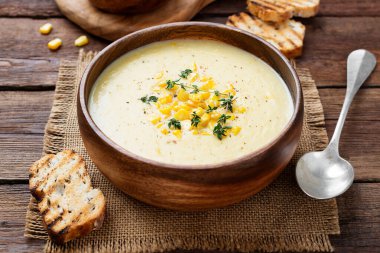 Delicious creamy sweetcorn soup served with toast and corn grains. clipart