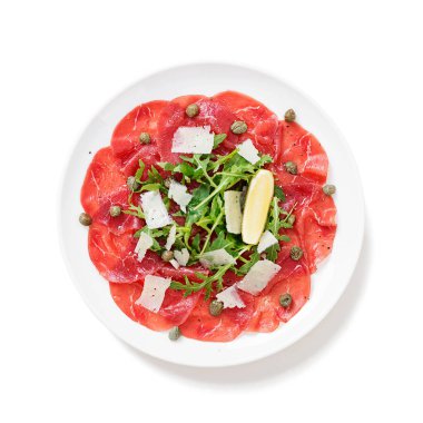 Carpaccio bifteği, parmesanlı soğuk aperatif kapari ve beyaz tabakta roka. beyaz arkaplanda izole