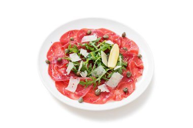 Carpaccio bifteği, parmesanlı soğuk aperatif kapari ve beyaz tabakta roka. beyaz arkaplanda izole