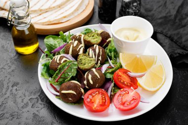 Yeşil salata, sos ve limonlu vejetaryen falafel..