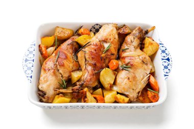 Baharatlı beyaz şarap, fırında sebze ve biberiyeyle birlikte tavşan bacağı. Beyaz arka planda izole edilmiş.