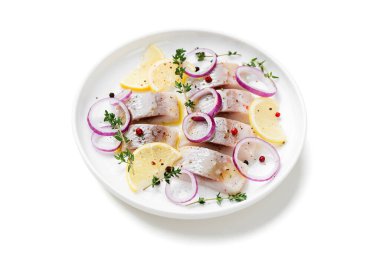 Baharatlı tuzlu ringa balığı, limon ve kırmızı soğan halkaları beyaz arka planda izole edilmiş. Salamura edilmiş balık..