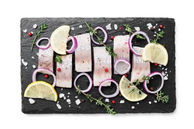 Baharatlı tuzlu ringa balığı, limon ve kırmızı soğan halkaları beyaz arka planda izole edilmiş. Salamura edilmiş balık. en üstteki görünüm