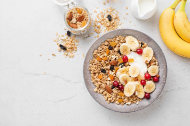 Sağlıklı kahvaltı. Taze granola, yoğurtlu müsli ve açık gri arka planda kızılcık. en üstteki görünüm