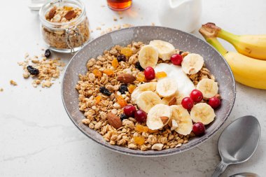 Healthy breakfast. Fresh granola, muesli with yogurt banana and cranberry on light gray background. clipart