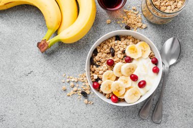 Sağlıklı kahvaltı. Taze granola, yoğurtlu müsli ve açık gri arka planda kızılcık. en üstteki görünüm