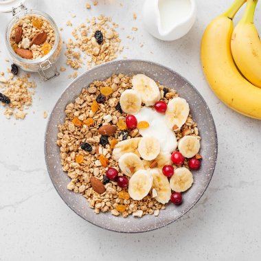 Sağlıklı kahvaltı. Taze granola, yoğurtlu müsli ve açık gri arka planda kızılcık. en üstteki görünüm