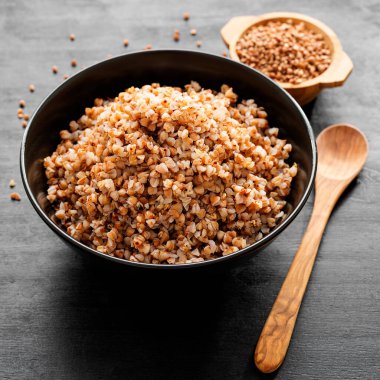 Lezzetli ve sağlıklı karabuğday lapası ve siyah ahşap arka planda tereyağı..