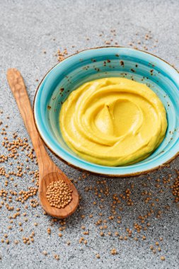Delicious organic mustard sauce in bowl with wooden spoon.		