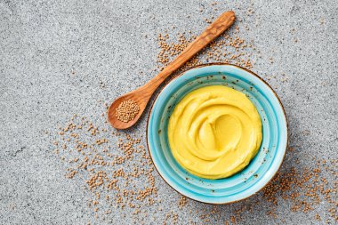 Delicious organic mustard sauce in bowl with wooden spoon.		
