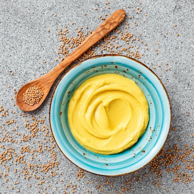 Delicious organic mustard sauce in bowl with wooden spoon.		