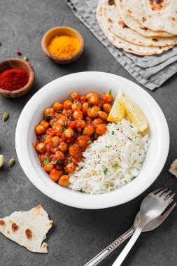 Traditional Indian dish chickpea chana masala with rice and flatbread.	