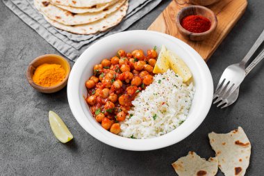 Traditional Indian dish chickpea chana masala with rice and flatbread.	