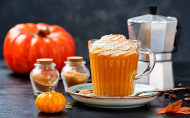 Pumpkin spice latte in a glass mug with cinnamon and nutmeg .	