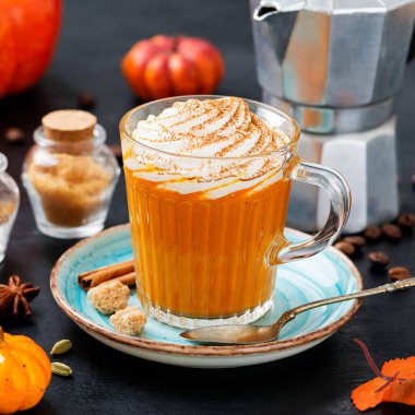 Pumpkin spice latte in a glass mug with cinnamon and nutmeg .	