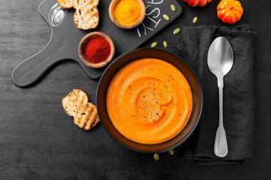 Pumpkin and carrot soup with spices on black background. Top view.	