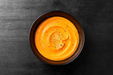 Pumpkin and carrot soup with spices on black background. Top view.	