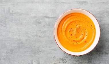 Pumpkin and carrot soup with spices on on grey stone background. Top view.	