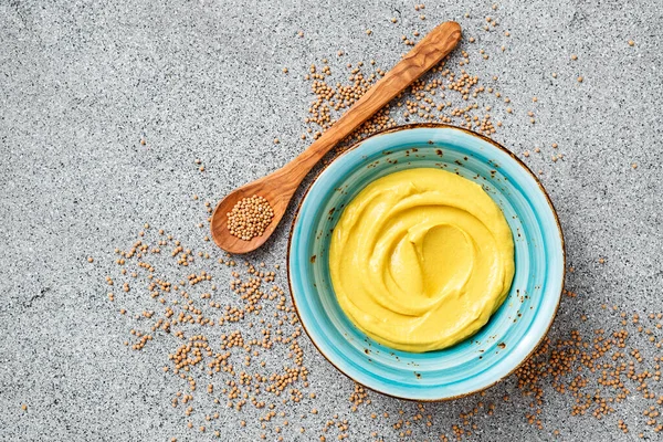 Delicious organic mustard sauce in bowl with wooden spoon.		
