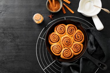 Tarçınlı Rolls Rulo, dökme demir tavada pişirildi. Siyah ahşap arka planda. Üst Wiev