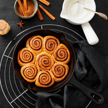 Tarçınlı Rolls Rulo, dökme demir tavada pişirildi. Siyah ahşap arka planda. Üst Wiev