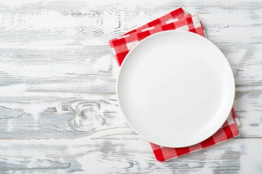 Boş beyaz tabak ve beyaz ahşap arka planda kırmızı peçete. Uzayı kopyala Üst görünüm