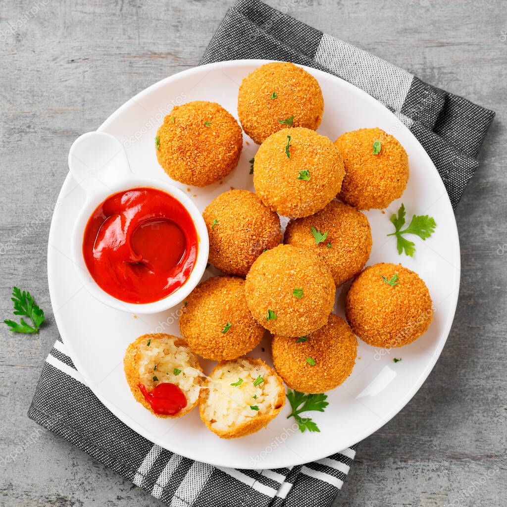 Homemade Fried Risotto Arancini stuffed with cheese, served with tomato sauce.