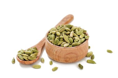 Beyaz arka planda izole edilmiş tahta bir kasede kakule kapsülleri..