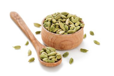 Beyaz arka planda izole edilmiş tahta bir kasede kakule kapsülleri..