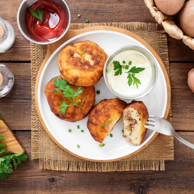 Patates köfteleri kıyma ile doldurulmuş, ekşi krema ve domates sosuyla servis edilmiş..