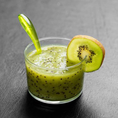 Siyah taş zemin üzerinde taze meyvelerle harmanlanmış kivi smoothie..