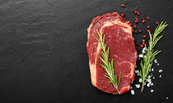 Çiğ et, siyah arka planda baharatlı biftek, üst manzara..