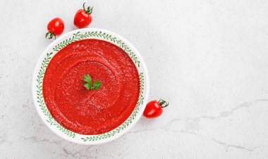Açık gri taşlı arka planda domates çorbası. Üst görünüm.