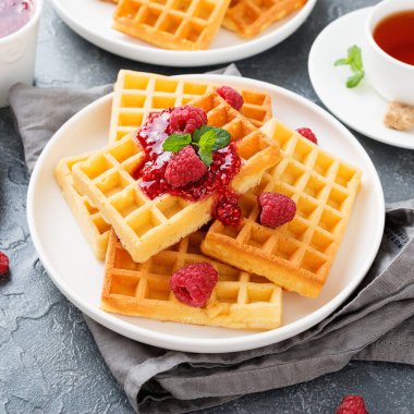 Gri arka planda taze ahududu ve reçelli geleneksel Belçika waffleları.