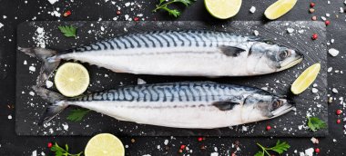 Taze balık. Siyah taş zemin üzerinde tuz, limon ve baharatlı uskumru..