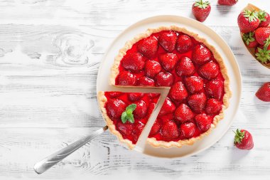 Beyaz ahşap arka planda lezzetli çilekli tart.