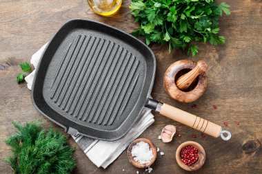 Ahşap arka planda yemek pişirmek için malzemeli boş dökme demir ızgara tavası, üst görünüm