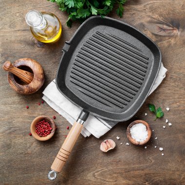 Ahşap arka planda yemek pişirmek için malzemeli boş dökme demir ızgara tavası, üst görünüm