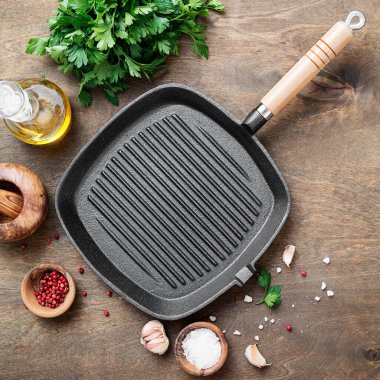 Ahşap arka planda yemek pişirmek için malzemeli boş dökme demir ızgara tavası, üst görünüm