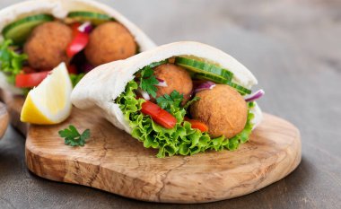 Falafel ve taze sebzeler ahşap masada pide.