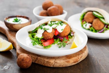 Falafel ve taze sebzeler ahşap masada pide.
